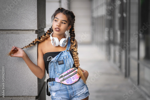 Young african girl thoughtfully looking aside while waiting friend at street