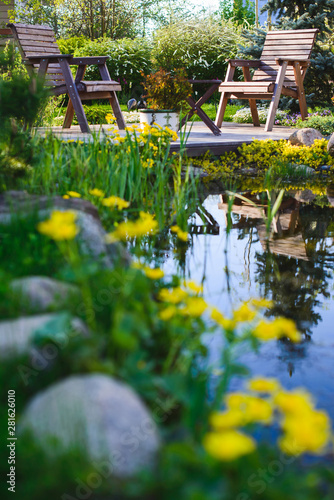 Two wooden chairs near the pond
