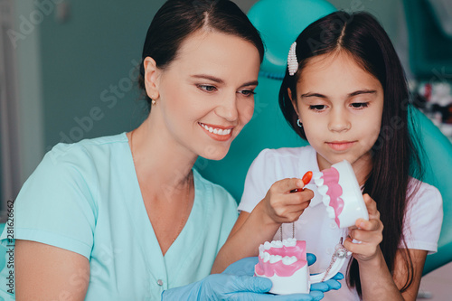 Mixed race girl showing how to brush teeth to her dentist, during a dental appointment