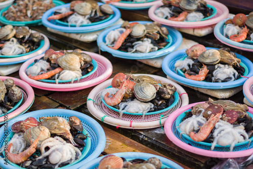 Busan, Korea, 12/22/2018 , fish displayed on a local market in the old part of Busan city in Korea. A mix of shells are already portioned on separate plates.