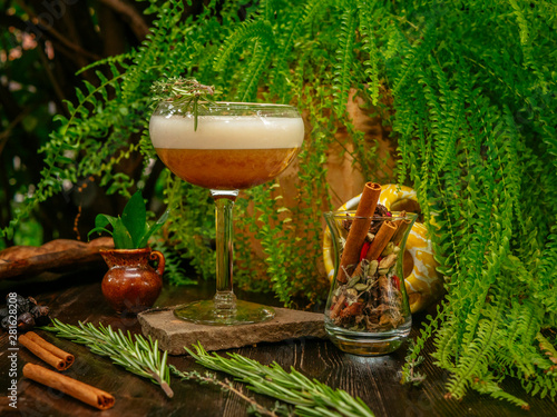 Brown cocktail in a glass goblet on a long leg. In the tropical garden. On a flat stone.