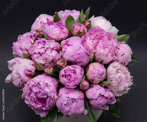 Pink peonies in a hat box on a dark background.