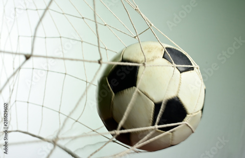 Scoring goal  Soccer ball in the net against gray background.