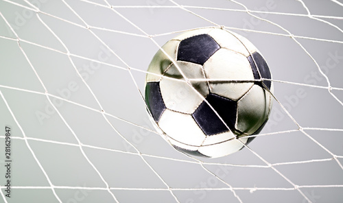 Scoring goal  Soccer ball in the net against gray background.