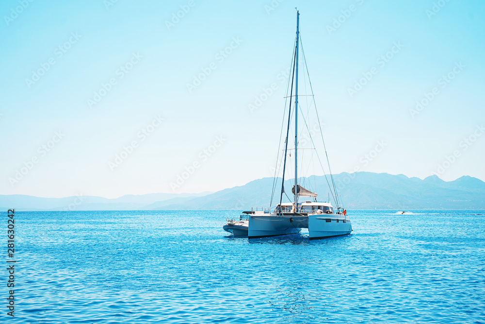 Sailing yacht catamaran boat in the sea in Greece, turquoise waters of Aegean Sea near Athens. Sailing yacht catamaran boat in the sea in Greece, turquoise waters of Aegean Sea near Athens.