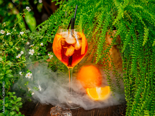 Orange aperol cocktail. On the summer terrace. Garden plants. Sunny day. Orange drink