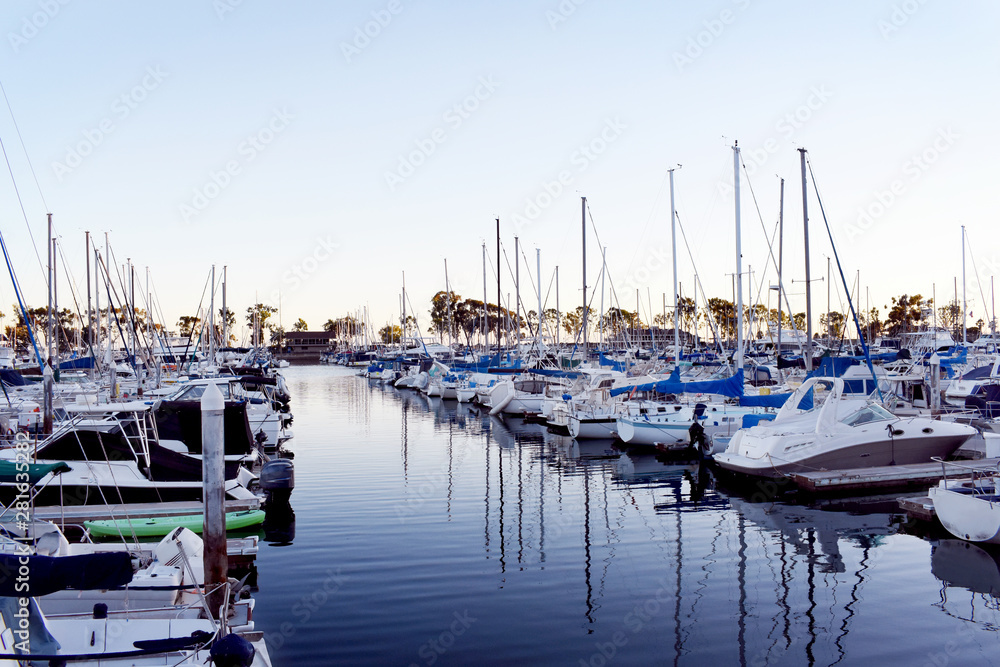 Dana Point marina with yachts, sailboats, reflection on water, at sunset