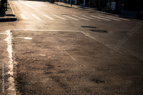 High contrast empty street with low sun near intersection and crosswalk markings in New York City.