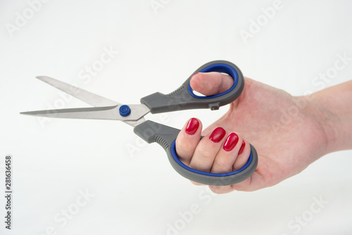 woman s hand with scissors  red nail Polish  white background 
