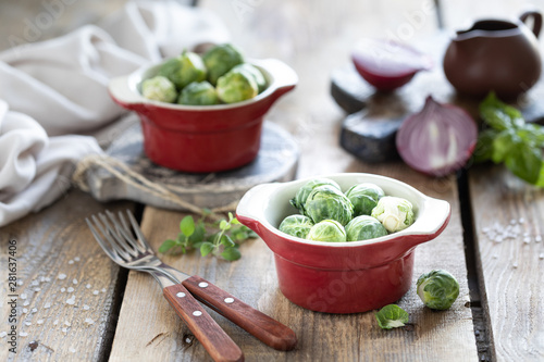 Young raw brussels sprouts in a metal cup on a wooden background