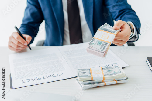 cropped view of businessman in formal wear gesturing near dollar banknotes