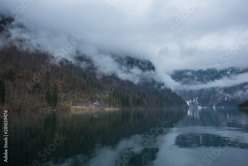 Tranquil scene of Konigssee lake in Germany in foggy day with a hut on the shore