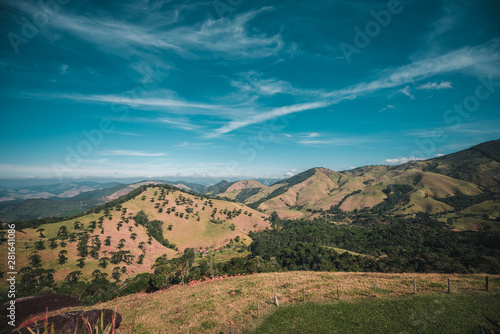 Green Hills and Mountains with Trees Under Blue Sky on Sunny Day