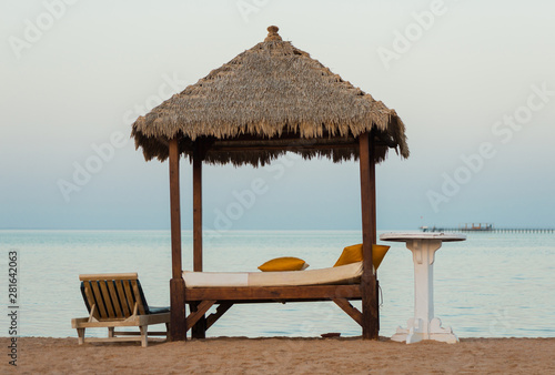 Fototapeta Naklejka Na Ścianę i Meble -  wooden sunbed construction with table  on a sand beach coastline sunset
