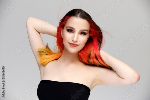 Studio portrait of a model with perfect makeup and colored hair on a white background. Beautiful female face of a pretty girl. Perfect makeup. Skin care. Fashionable cosmetics.