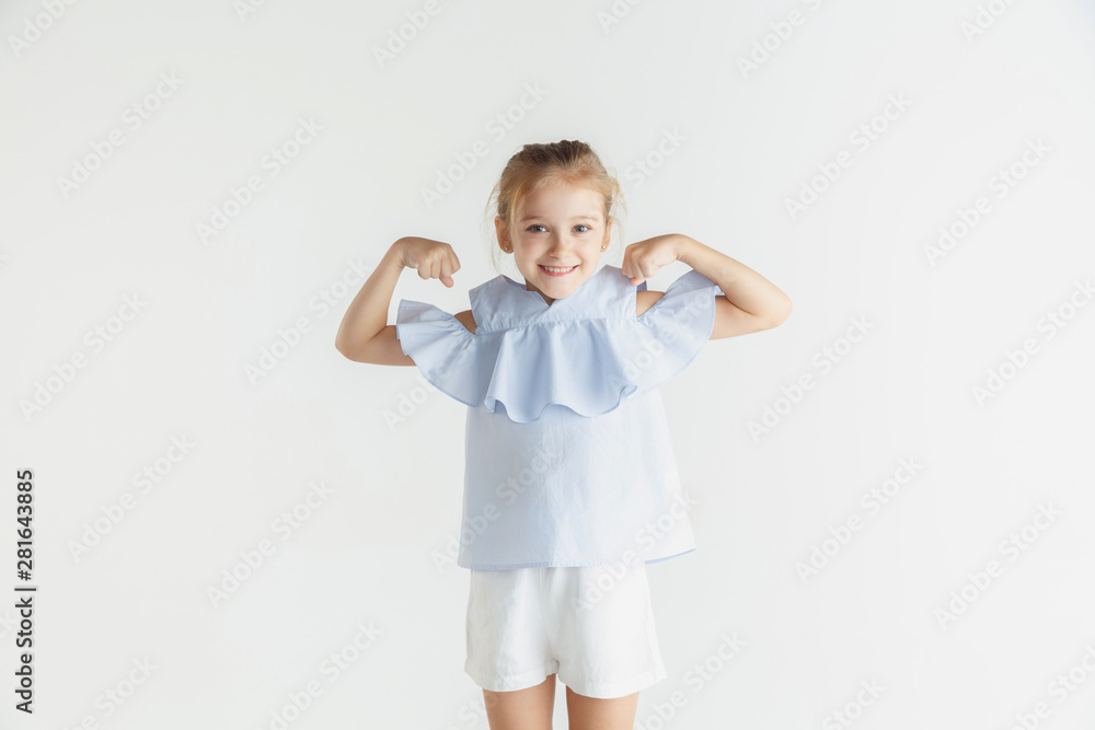 Stylish little smiling girl posing in casual clothes isolated on white studio background. Caucasian blonde female model. Human emotions, facial expression, childhood. Winning, celebrating, smiling. Stylish little smiling girl posing in casual clothes isolated on white studio background. Caucasian blonde female model. Human emotions, facial expression, childhood. Winning, celebrating, smiling.