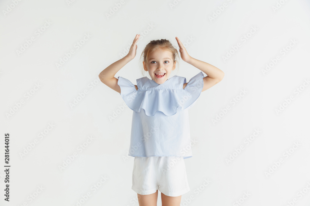 Stylish little smiling girl posing in casual clothes isolated on white studio background. Caucasian blonde female model. Human emotions, facial expression, childhood. Looks happy and amazed. Stylish little smiling girl posing in casual clothes isolated on white studio background. Caucasian blonde female model. Human emotions, facial expression, childhood. Looks happy and amazed.