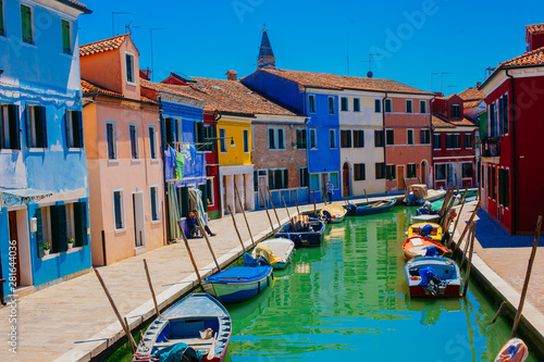 Colorful houses along a green canal with old boats in Burano Italy © Kirill