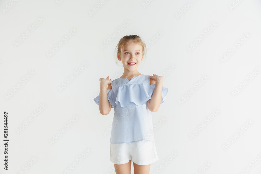 Stylish little smiling girl posing in casual clothes isolated on white studio background. Caucasian blonde female model. Human emotions, facial expression, childhood. Showing, inviting or greeting. Stylish little smiling girl posing in casual clothes isolated on white studio background. Caucasian blonde female model. Human emotions, facial expression, childhood. Showing, inviting or greeting.