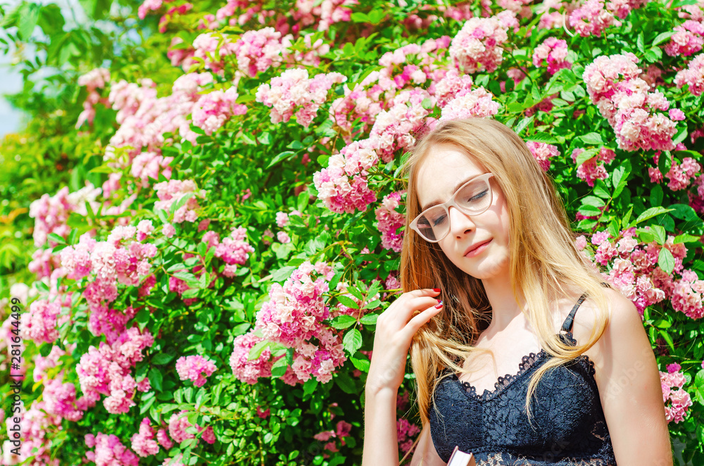 Nice girl in glasses with white hair on a background of a flowering rose bush Nice girl in glasses with white hair on a background of a flowering rose bush