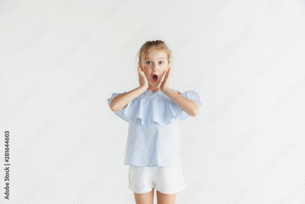 Stylish little smiling girl posing in casual clothes isolated on white studio background. Caucasian blonde female model. Human emotions, facial expression, childhood, sales. Shocked, astonished. Stylish little smiling girl posing in casual clothes isolated on white studio background. Caucasian blonde female model. Human emotions, facial expression, childhood, sales. Shocked, astonished.