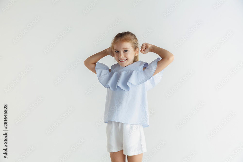 Stylish little smiling girl posing in casual clothes isolated on white studio background. Caucasian blonde female model. Human emotions, facial expression, childhood. Winning, celebrating, smiling. Stylish little smiling girl posing in casual clothes isolated on white studio background. Caucasian blonde female model. Human emotions, facial expression, childhood. Winning, celebrating, smiling.