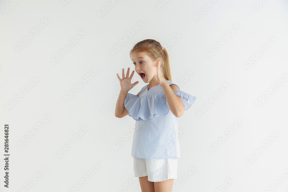 Stylish little smiling girl posing in casual clothes isolated on white studio background. Caucasian blonde female model. Human emotions, facial expression, childhood, sales. Shocked, astonished. Stylish little smiling girl posing in casual clothes isolated on white studio background. Caucasian blonde female model. Human emotions, facial expression, childhood, sales. Shocked, astonished.
