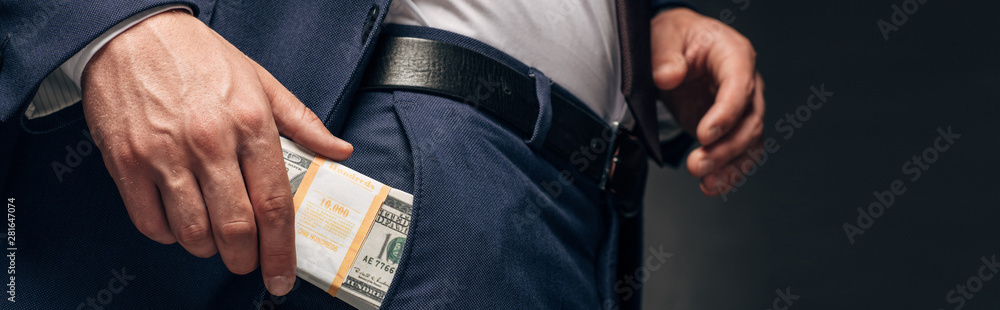 panoramic shot of businessman putting cash in pocket on grey