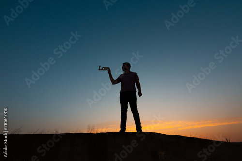 silhouette of man with poster that puts love