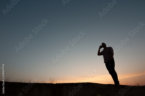 silhouette of man with cell phone at sunset