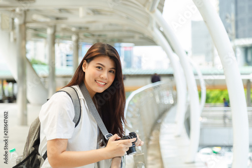 Portrait of young charming Asian woman wearing in white shirt, holding camera on her