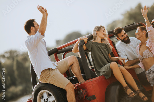 Group of young people  having fun by car outdoor at hot summer day © BGStock72