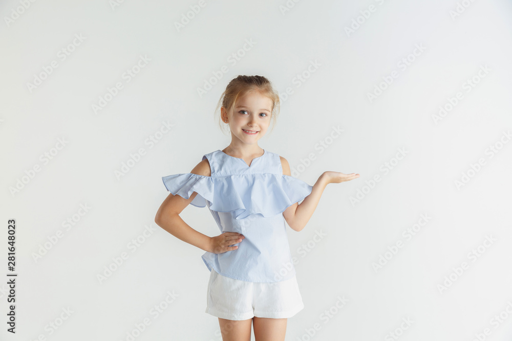 Stylish little smiling girl posing in casual clothes isolated on white studio background. Caucasian blonde female model. Human emotions, facial expression, childhood. Showing empty space, inviting Stylish little smiling girl posing in casual clothes isolated on white studio background. Caucasian blonde female model. Human emotions, facial expression, childhood. Showing empty space, inviting
