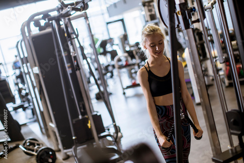 Young sporty woman working out on pull-down machine in gym