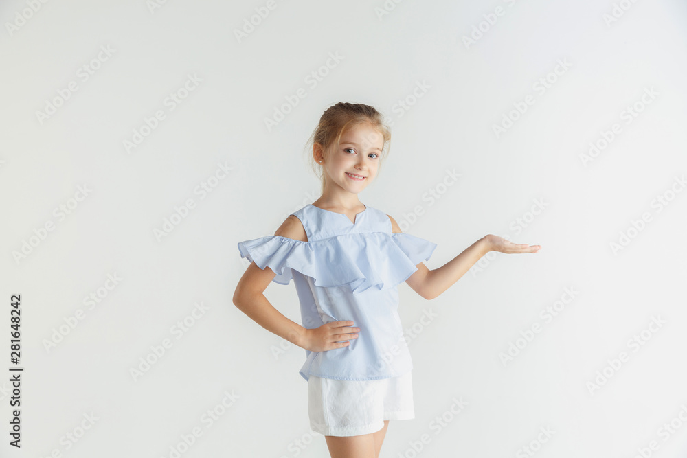 Stylish little smiling girl posing in casual clothes isolated on white studio background. Caucasian blonde female model. Human emotions, facial expression, childhood. Showing empty space, inviting Stylish little smiling girl posing in casual clothes isolated on white studio background. Caucasian blonde female model. Human emotions, facial expression, childhood. Showing empty space, inviting