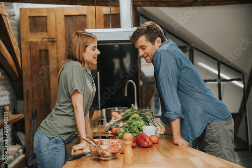 Beautiful young couple smiling while cooking in kitchen at home
