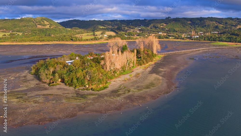 Aerial view with drone of the iconic Aucar Island that has a bridge made of wood. This island that is near the town of Quemchi in the Chiloé archipelago 