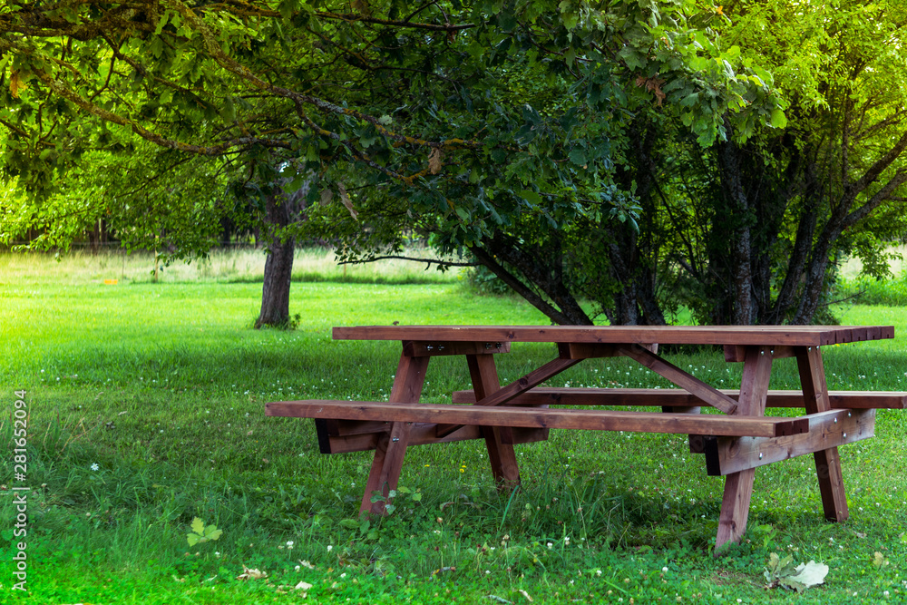 Wooden bench and table on a meadow in the garden on the old Alpaca Farm. Summer leisure time in the nature. Tranquil nature day scene. Wooden bench and table on a meadow in the garden on the old Alpaca Farm. Summer leisure time in the nature. Tranquil nature day scene.