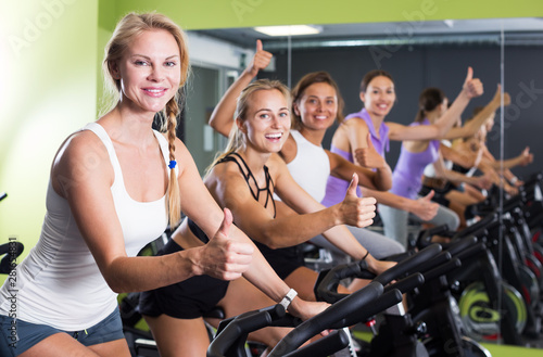 Satisfied women cycling in gym