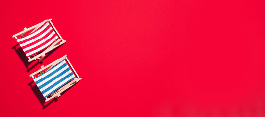 Flat lay of beach deck chairs on red background with copy space. Summer and travel concept. Creative banner