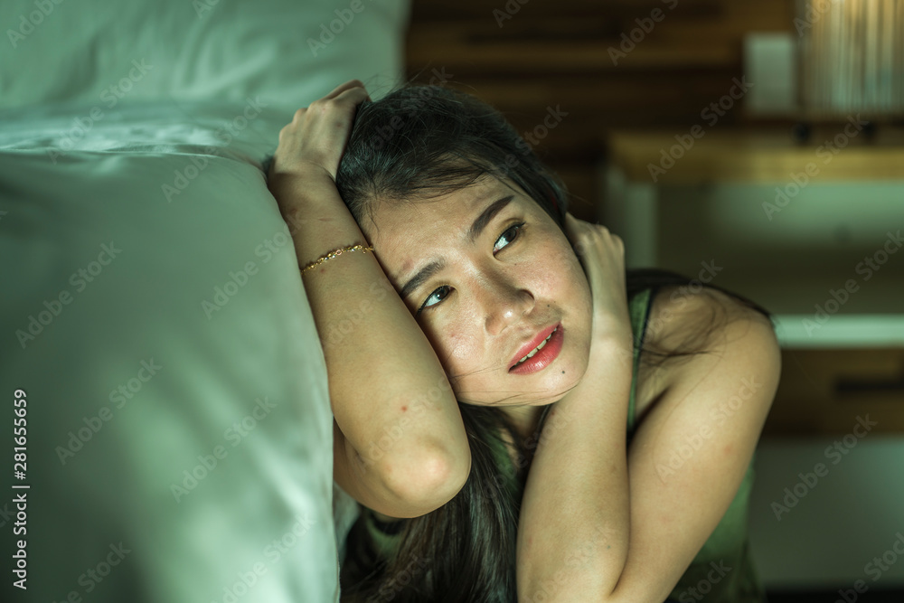 Fototapeta premium young depressed and sad Asian Japanese woman sitting on floor at bedroom next to bed suffering depression problem and anxiety crisis feeling desperate