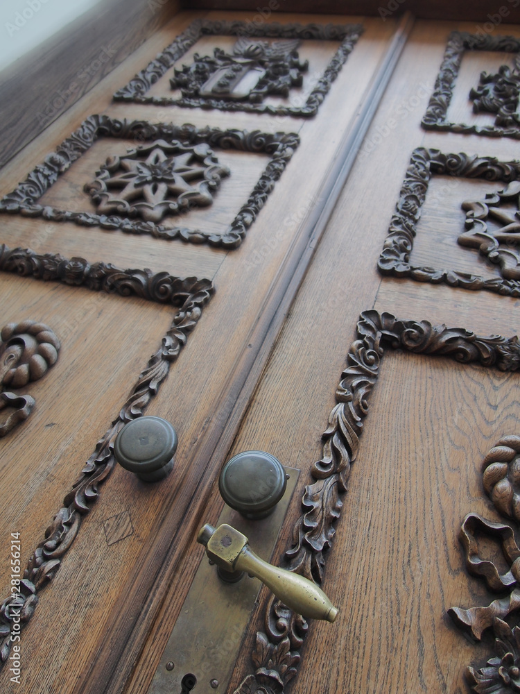 Antic massive wooden door with graceful carving ornamemt and bronze metal handles Antic massive wooden door with graceful carving ornamemt and bronze metal handles