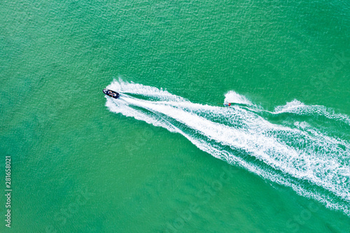 Wake boarder towed by jetski in blue waters © Zstock