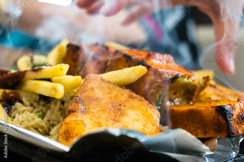 Delicious paneer, french fries and vegetble sizzler giving off smoke and steam photo