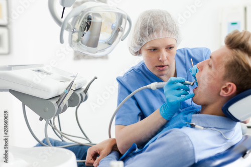 Male patient sitting on chair in dental office getting dentist treatment