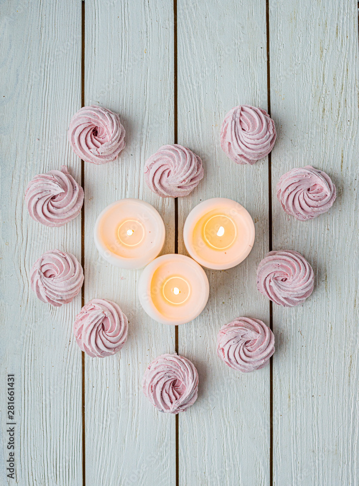 Zephyr lined in a heart shape with burning candles on a white background. Flat lay. Top view. Pink sweet homemade zephyr or marshmallow. Colorful meringues on white. top view dessert image. Zephyr lined in a heart shape with burning candles on a white background. Flat lay. Top view. Pink sweet homemade zephyr or marshmallow. Colorful meringues on white. top view dessert image.