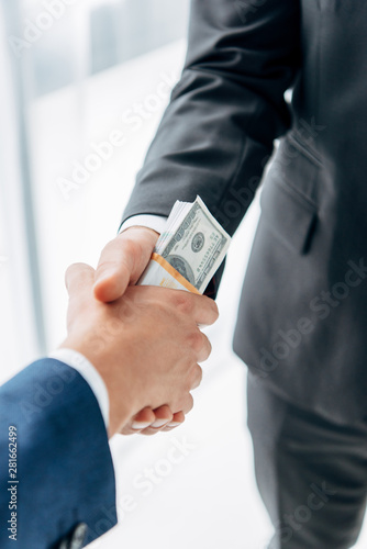 Fototapet cropped view of businessman giving bribe to business partner while shaking hands