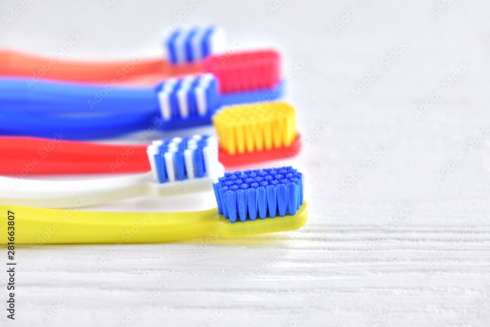 Colorful toothbrushes with selective focus on blurred neutral background. Dental tools for daily teeth protection. Multicolored plastic toothbrush with bright bristles with soft focus. Oral hygiene Colorful toothbrushes with selective focus on blurred neutral background. Dental tools for daily teeth protection. Multicolored plastic toothbrush with bright bristles with soft focus. Oral hygiene
