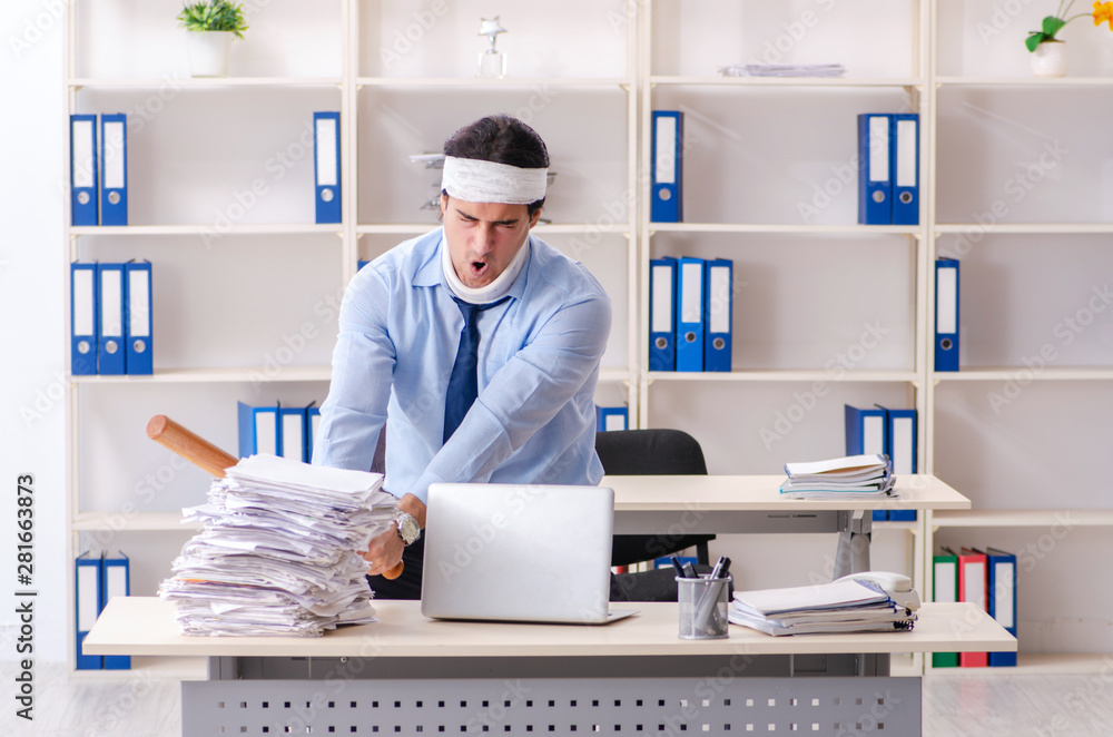 Young injured male employee working in the office Young injured male employee working in the office