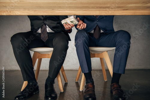 Photos cropped view man giving bribe to business partner while sitting on chair